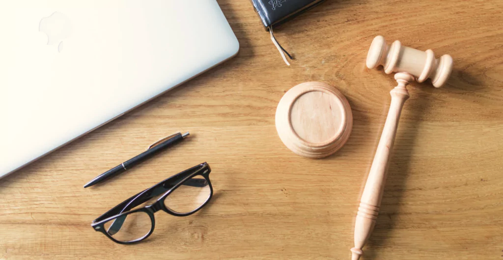 Martelo de juiz de madeira, óculos de grau e caneta sobre uma mesa de escritório rústica