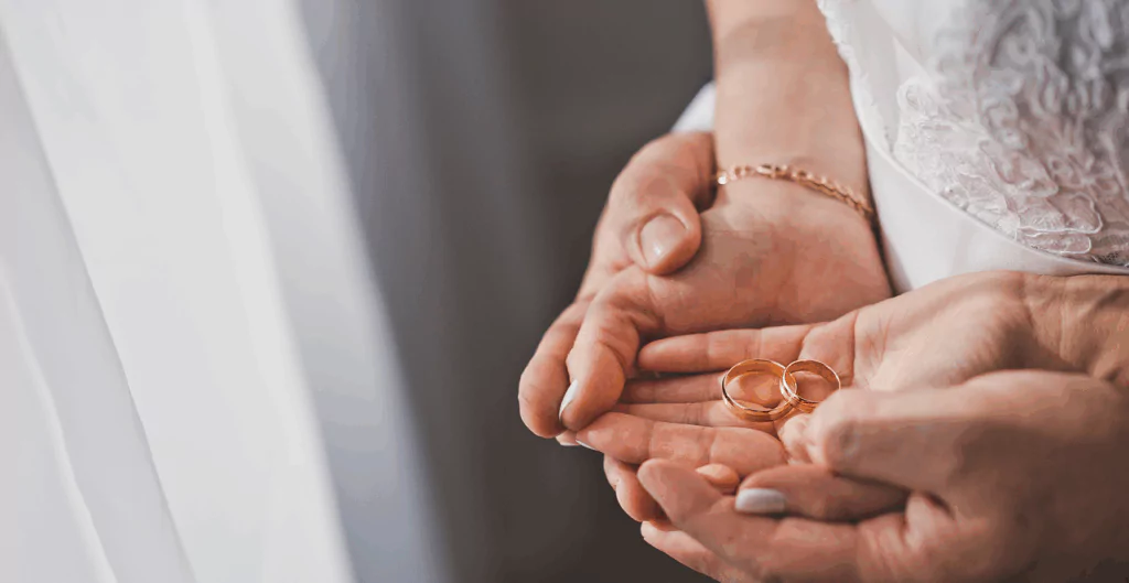 imagem de duas mãos segurando duas alianças de compromisso, representando a licença casamento