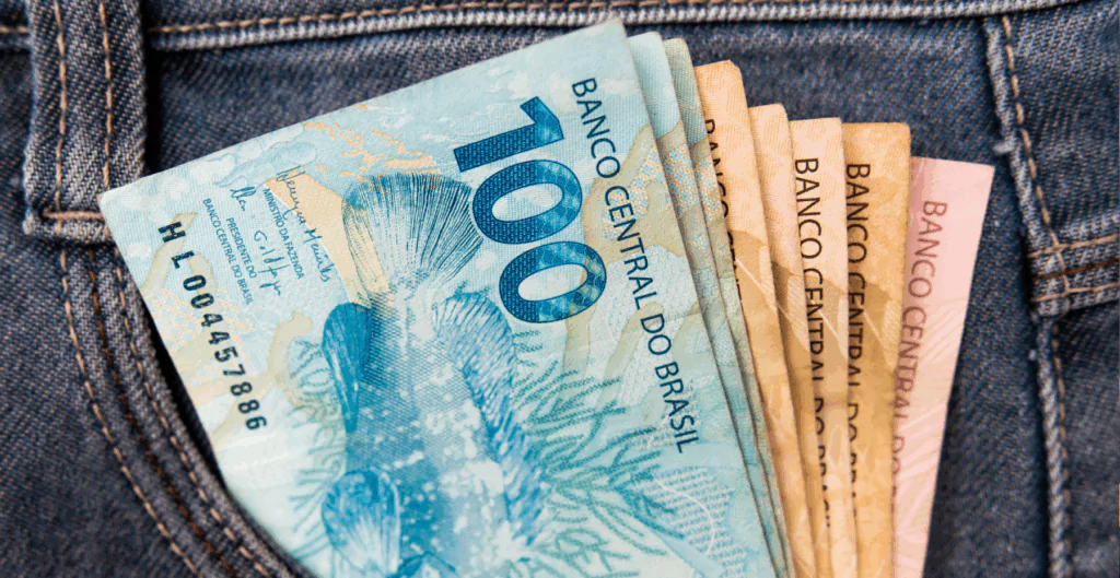 Notas de cinquenta e cem reais no bolso de uma calça jeans