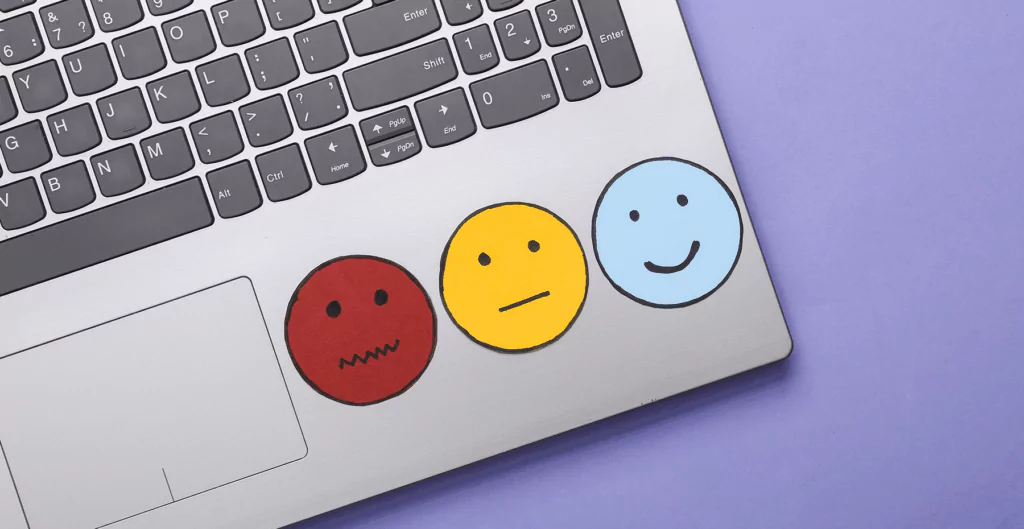 Notebook com adesivos do humor, com fundo roxo no fundo.