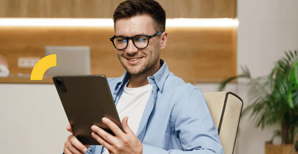 Homem sorrindo olhando para um tablet 