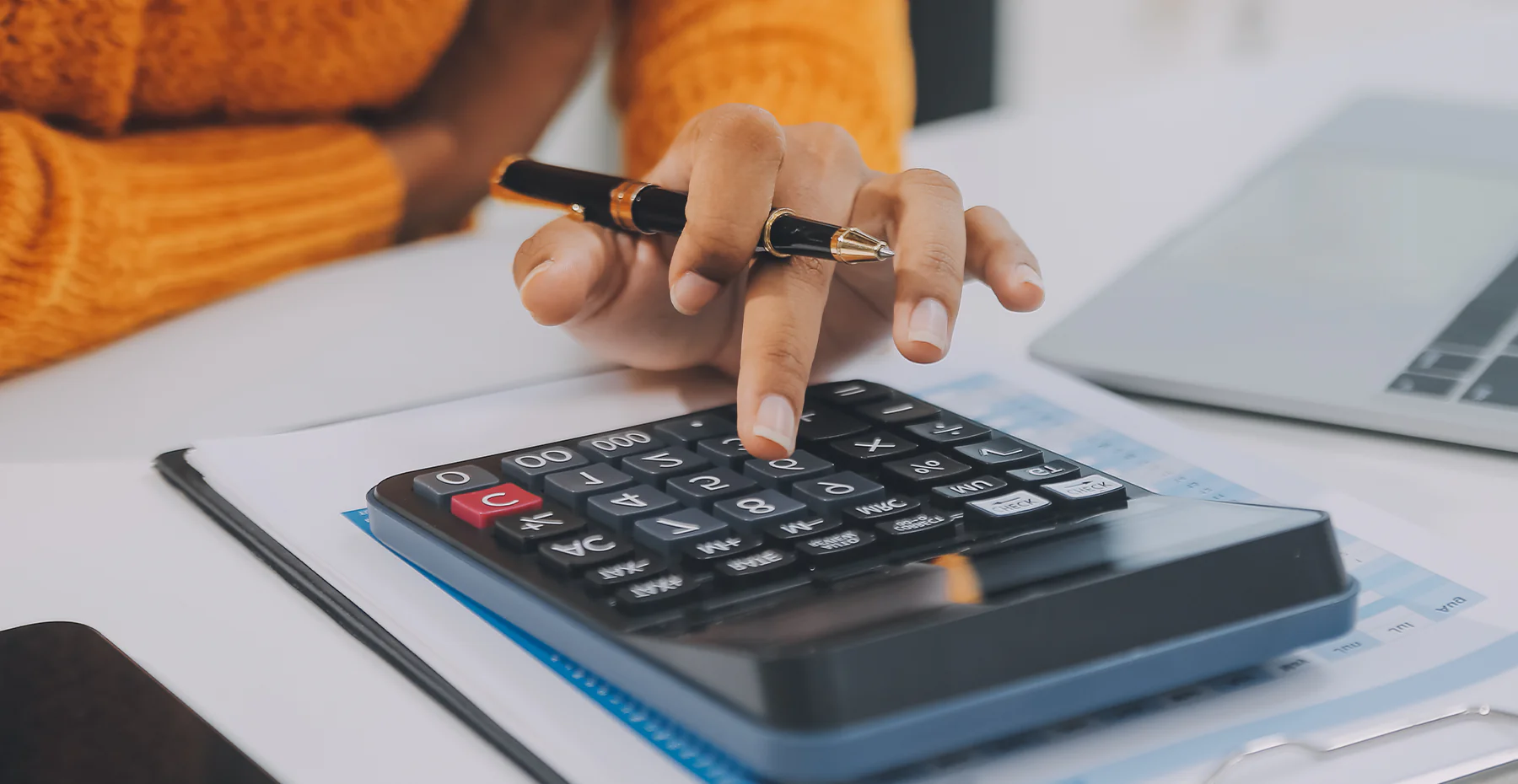 Pessoa digitando em uma calculadora grande enquanto trabalha.