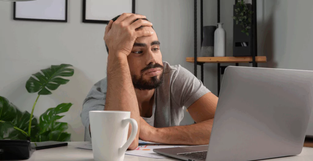 Colaborador desmotivado diante do computador, ilustrando os impactos da baixa produtividade no home office.