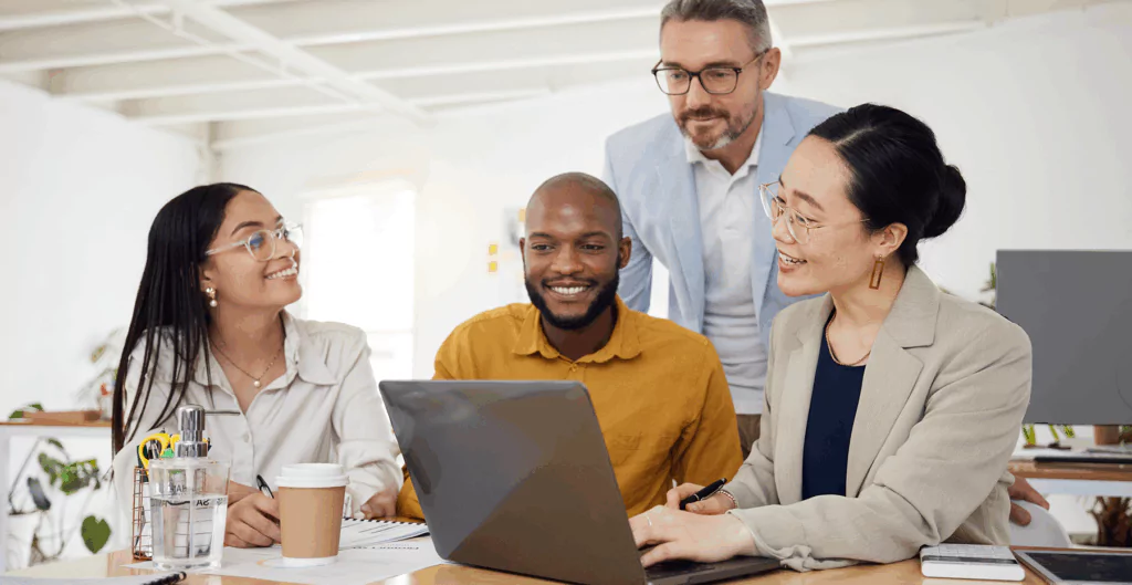 duas mulheres e dois homens sorrindo para um notebook