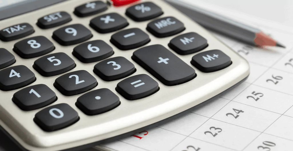 Calculadora de mesa sobre uma planilha com datas, representando contabilidade ou gestão financeira.