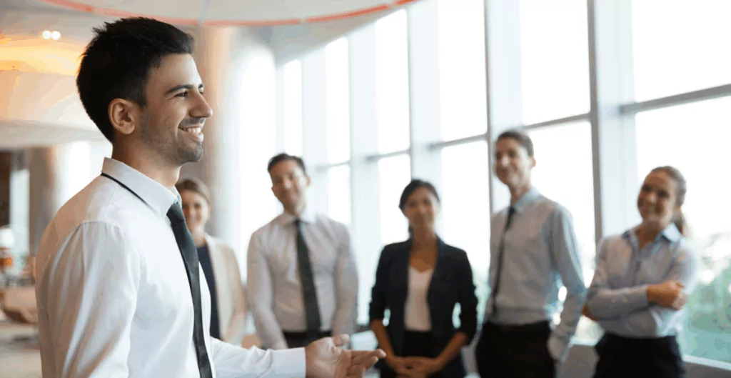 Homem sorrindo, com outras pessoas olhando ao fundo