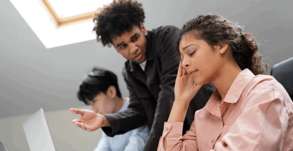 Mulher com a mão na cabeça, com homem falando ao lado com mão para o alto