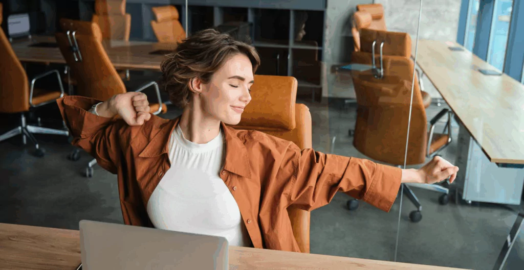 Mulher se espreguiçando em escritório vazio ao fundo