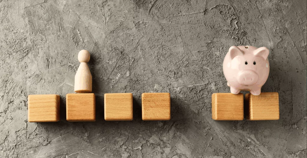 Cubos de madeira, ícone de pessoa e um cofre em formato de porco de porcelana