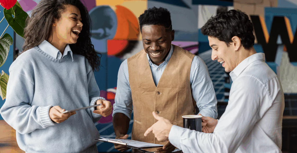 Três pessoas sorrindo e conversando em ambiente de trabalho criativo, com destaque para a saúde organizacional, promovendo colaboração e inovação.