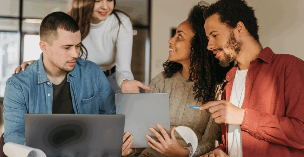 Pessoas conversando e segurando um tablet e um notebook