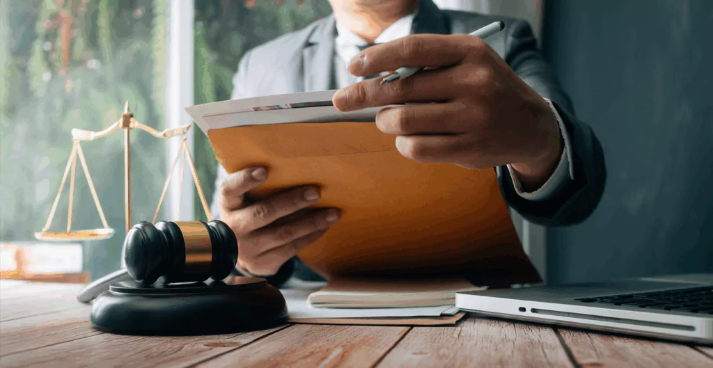 Advogado analisando documentos jurídicos em escritório de advocacia, com balança de justiça ao fundo, simbolizando direito e legalidade.