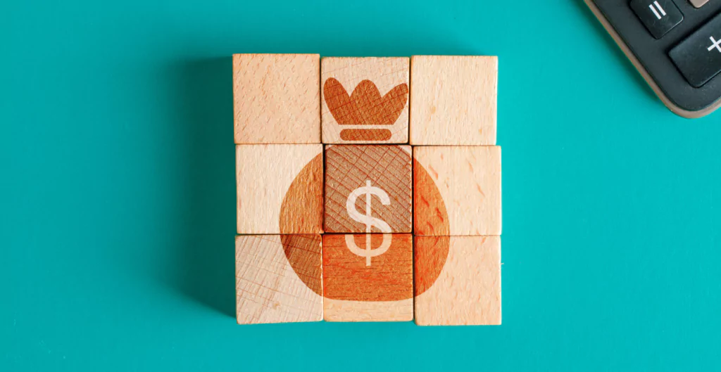 Cubos de madeira formando o desenho de um saco de dinheiro com cifrão.