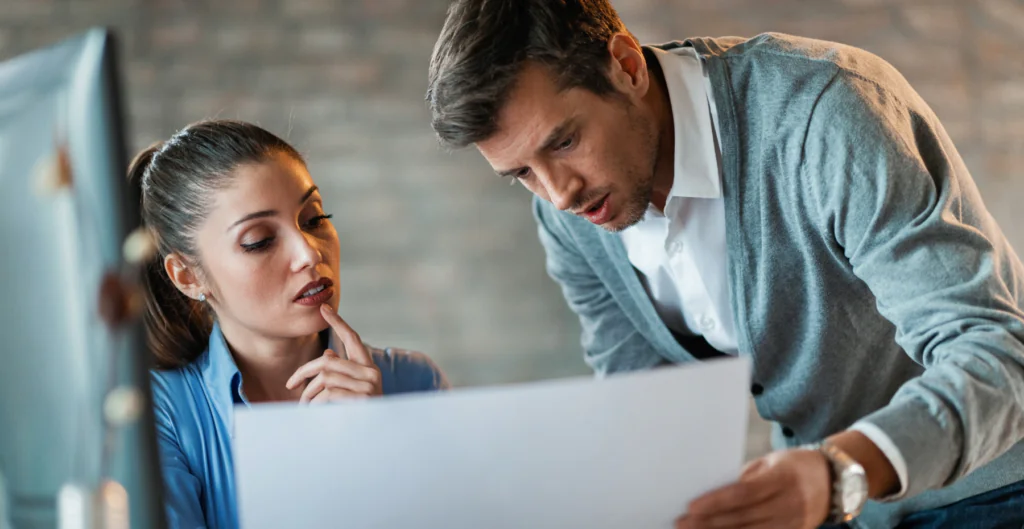 Dois profissionais em escritório analisando documento sobre pedido de demissão depois do fechamento da folha