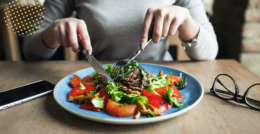 mãos de uma pessoa caucasiana comendo um prato de salada