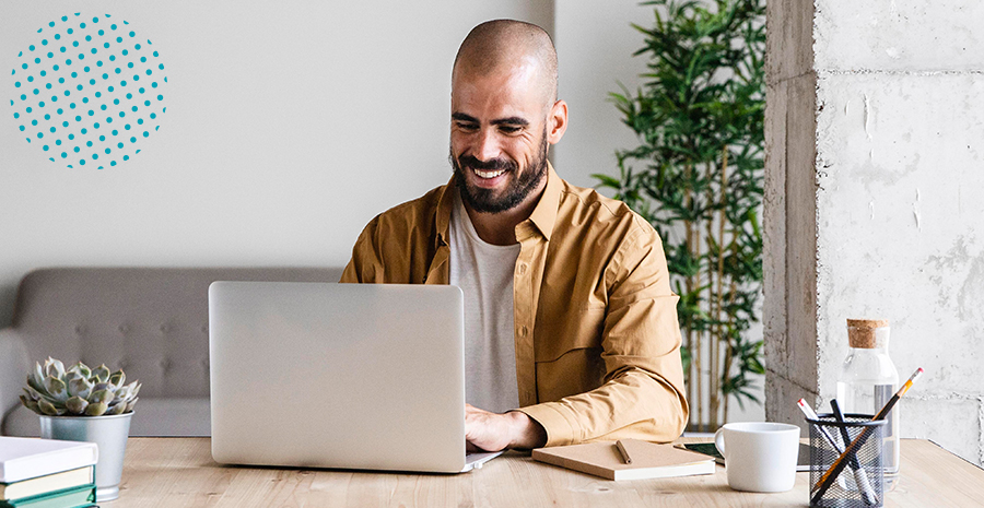 imagem de um homem sentado sorrindo mexendo em um computador