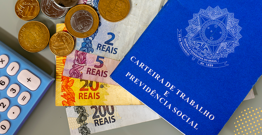 imagem de uma carteira de trabalho ao lado de notas de dinheiro e moedas