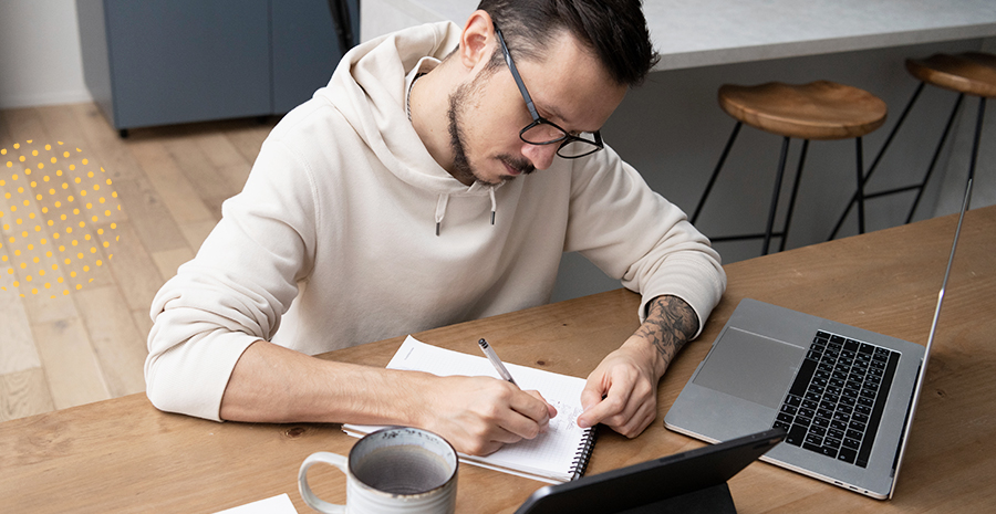 imagem de um homem sentado escrevendo em um caderno