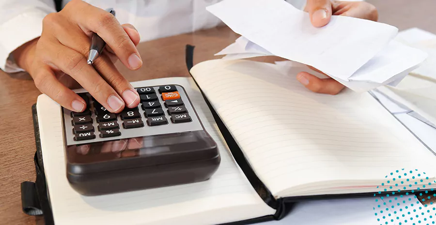 imagem de uma pessoa usando uma calculadora e segurando uma folha de papel