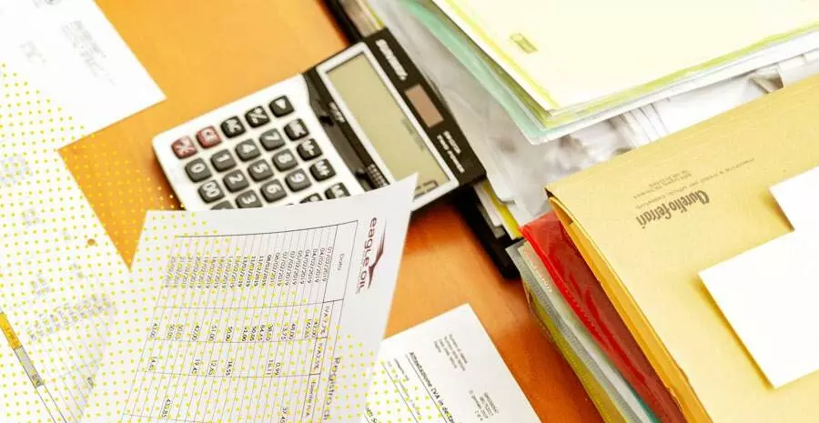 imagem de uma mesa de trabalho com calculadora e papeis