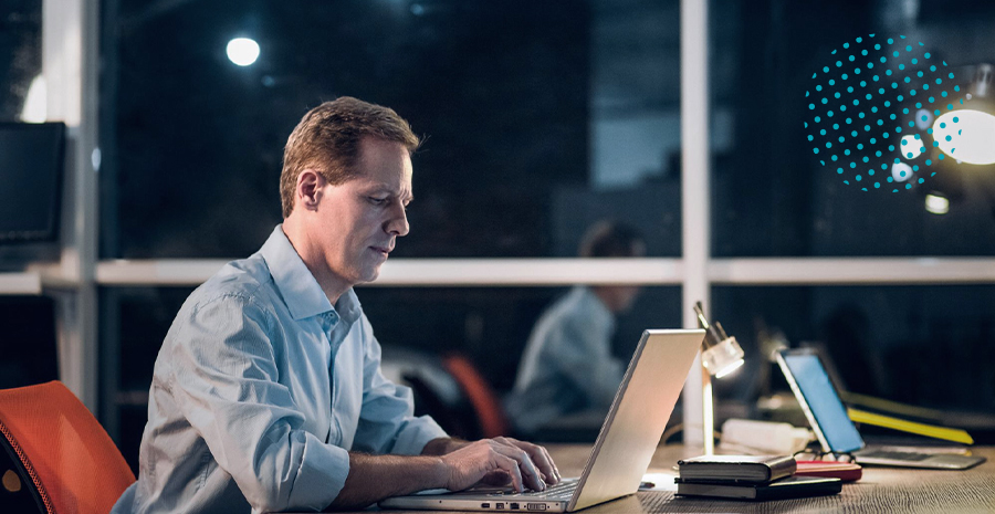 imagem de um homem sentado trabalhando com um notebook a noite realizando a compensação de horas