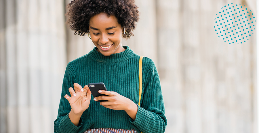 mulher segurando o celular e sorrindo em um ambiente externo