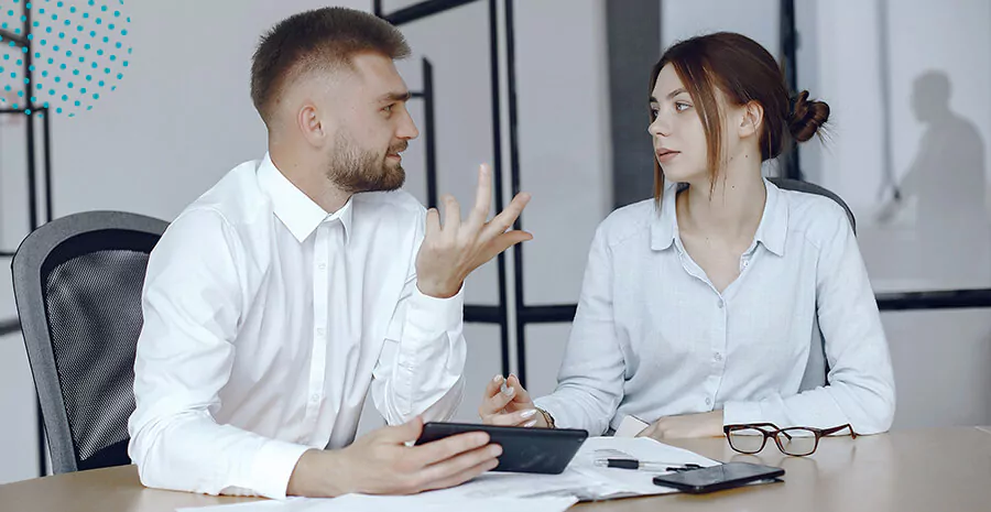 duas pessoas sentadas conversando, imagem de uma mesa com papéis, calculadoras e etc