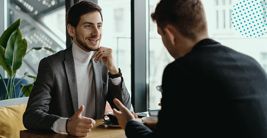 dois homens sentados, um de frente e um de costas conversando civilizadamente