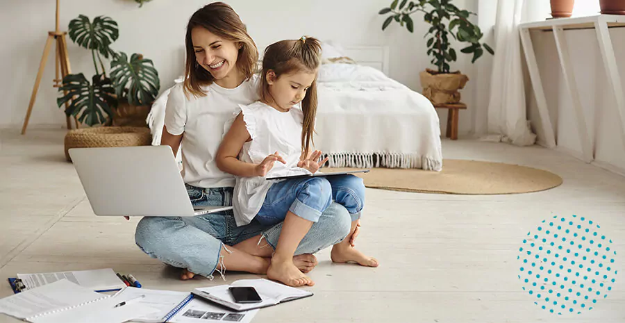 imagem de uma mulher brincando com sua filha enquanto trabalha representando os benefícios do trabalho remoto
