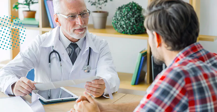 imagem deum homem sentado na frente de um senhor que usa jaleco, ele é médico