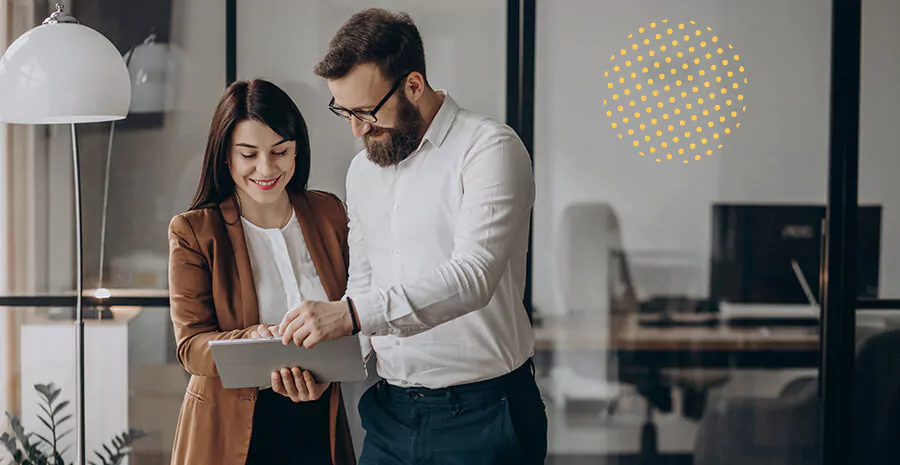 imagem de um homem e uma mulher analisando um tablet em um ambiente corporativo