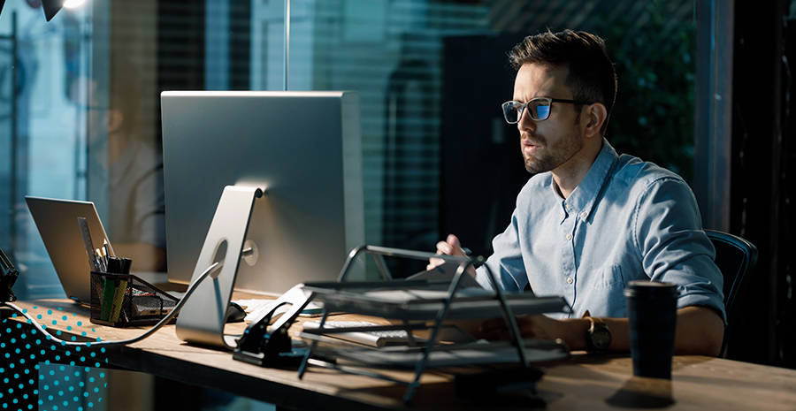 Imagem de um homem trabalhando em um escritório mexendo em um computador