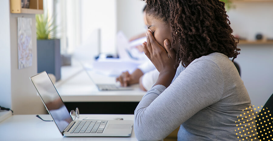 imagem de uma mulher com a mão no rosto aparentemente triste em frente a um computador