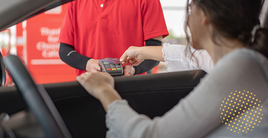 imagem de uma mulher, no posto da gasolina, pagando com o cartão