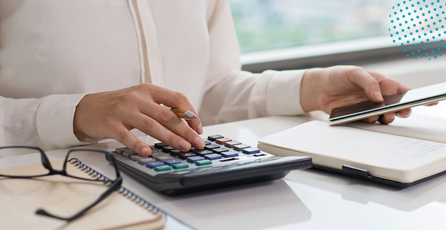 imagem de uma pessoa com uma caneta na mão e uma calculadora na mesa