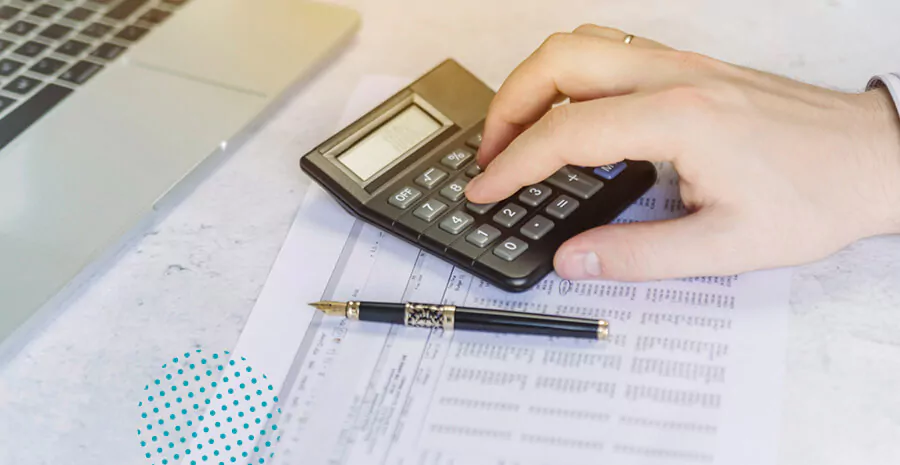 imagem com foco em uma mão digitando números em calculadora