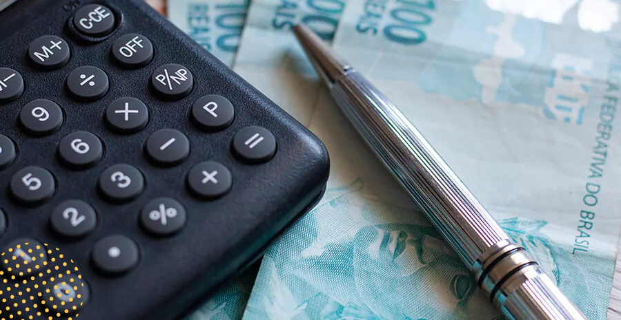 imagem de uma calculadora, caneta e notas de cem reais