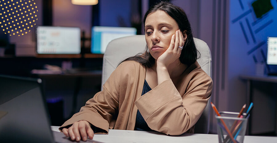 imagem de uma mulher em uma mesa de trabalho com expressão triste e cansada