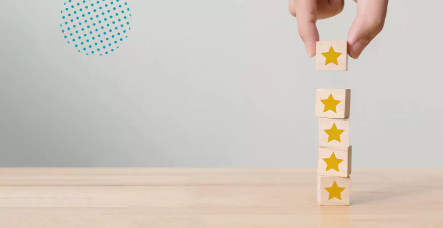imagem de quatro cubos empilhados em cima de uma mesa e uma mão acrescentando mais um cubo com desenho de estrela