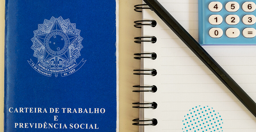 imagem de uma carteira de trabalho do lado de um caderno branco