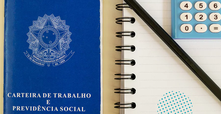 imagem de uma carteira de trabalho do lado de um caderno branco
