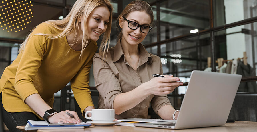 imagem de duas mulheres olhando para um computador e sorrindo