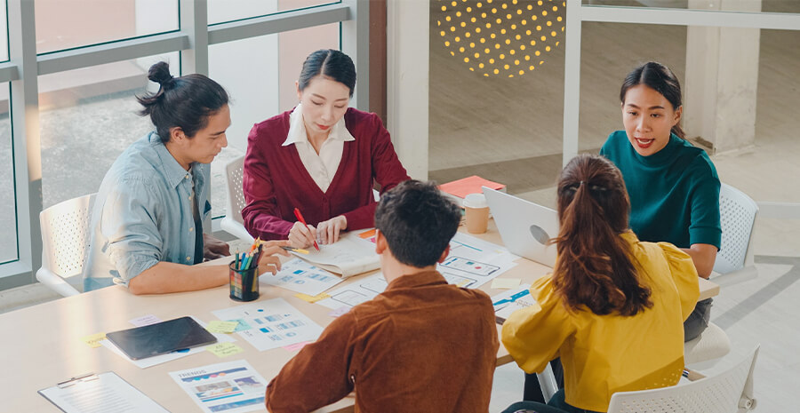 imagem de pessoas com roupas coloridas reunidas em uma mesa de reunião