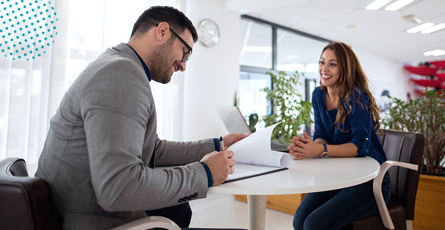 imagem de um homem e uma mulher sentados conversando e o homem preenchendo um papel