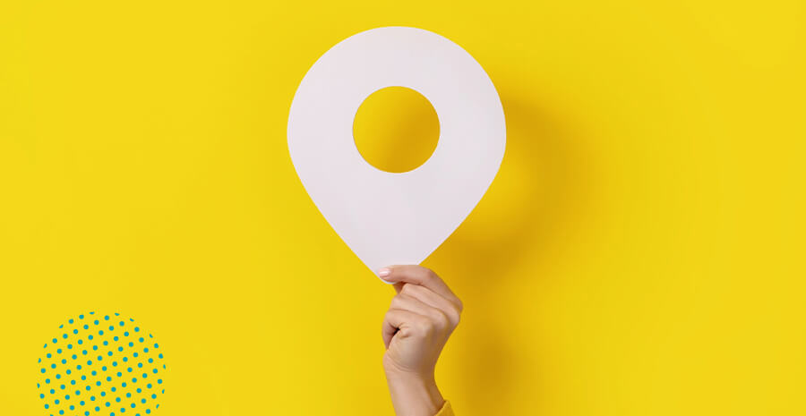 imagem de uma mão segurando um pino de localização em um fundo amarelo