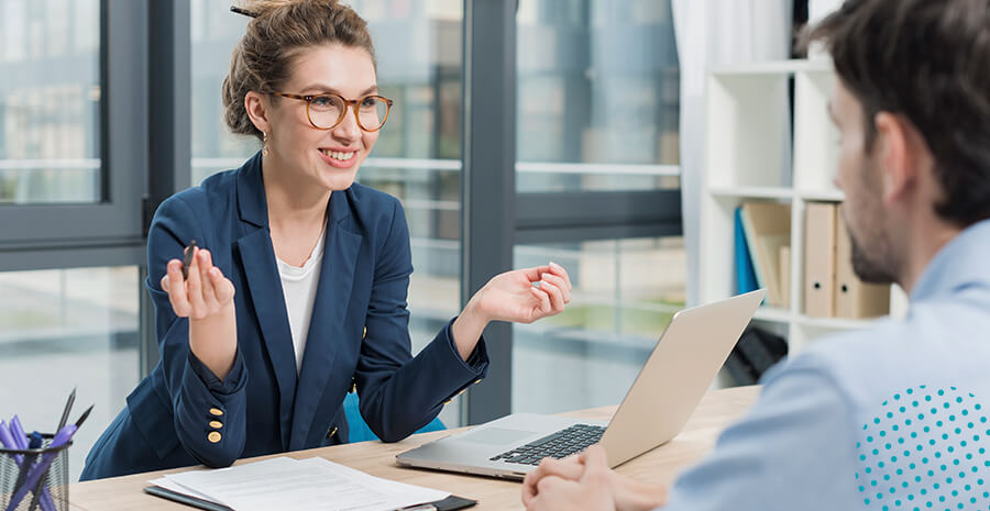 imagem de uma mulher sorrindo em um escritório na frente de um computador e de um homem