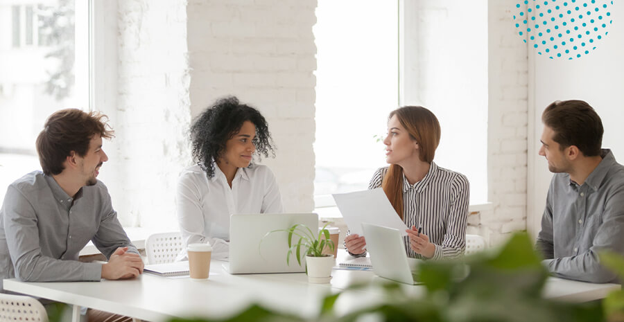 imagem de duas mulheres e dois homens sentados ao redor de uma mesa se olhando