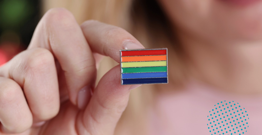 imagem de uma pessoa segurando um broche da bandeira lgbt+