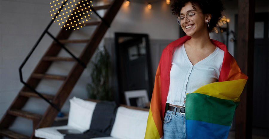 imagem de uma mulher sorrindo segurando a bandeira lgbt+