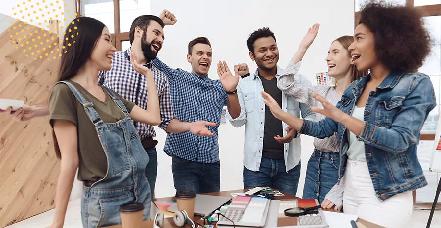 imagem de um grupo de pessoas em pé ao redor de uma mesa sorrindo e celebrando